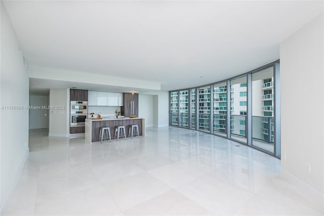 living room featuring floor to ceiling windows, light tile flooring, and sink