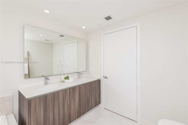 bathroom with double sink vanity, tile floors, and a bath to relax in