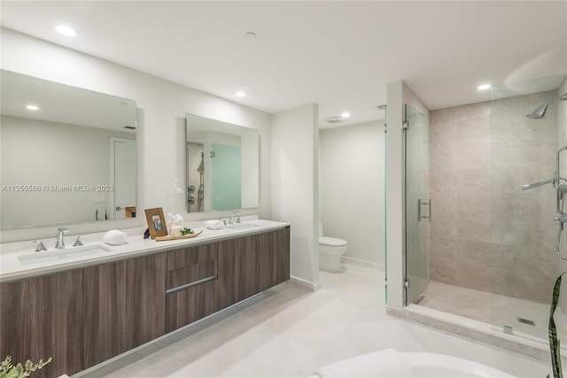 bathroom featuring tile floors, dual sinks, a shower with door, vanity with extensive cabinet space, and toilet