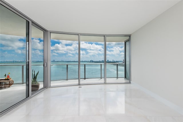 tiled spare room with expansive windows and a water view