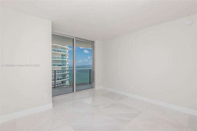 tiled empty room with a wall of windows and a water view