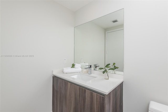 bathroom with toilet and vanity with extensive cabinet space