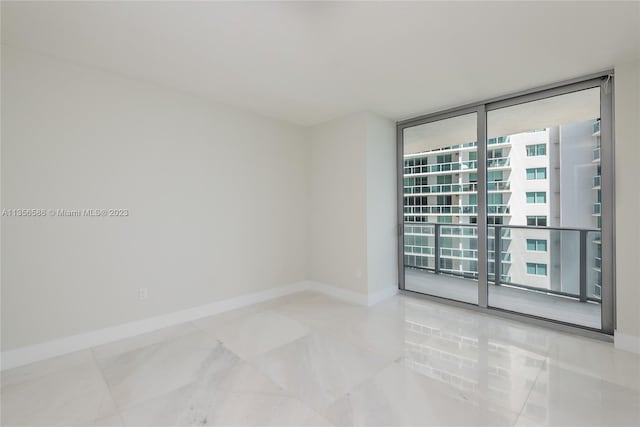 empty room featuring light tile flooring, a healthy amount of sunlight, and a wall of windows