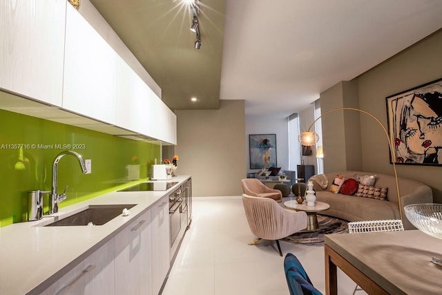 kitchen featuring black electric stovetop, white cabinetry, light tile floors, and sink