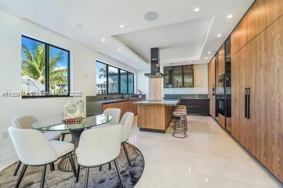 dining area featuring a raised ceiling, a wealth of natural light, and wood walls