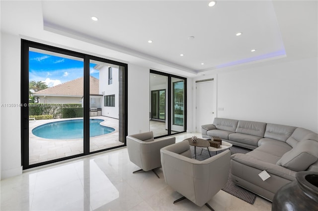 living room featuring a raised ceiling and floor to ceiling windows