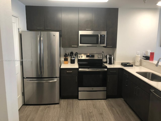 kitchen with stainless steel appliances, light wood-type flooring, and sink