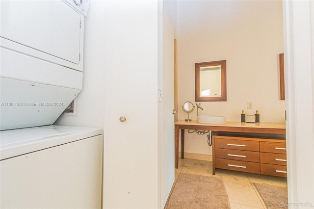 laundry room featuring stacked washer / dryer, sink, and light tile patterned floors