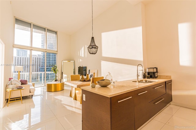 kitchen featuring sink, high vaulted ceiling, pendant lighting, dark brown cabinets, and light tile patterned floors