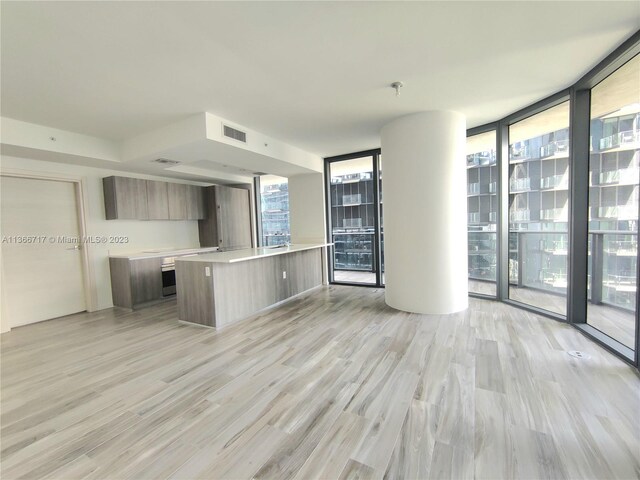 kitchen with floor to ceiling windows, a kitchen island, and light hardwood / wood-style flooring