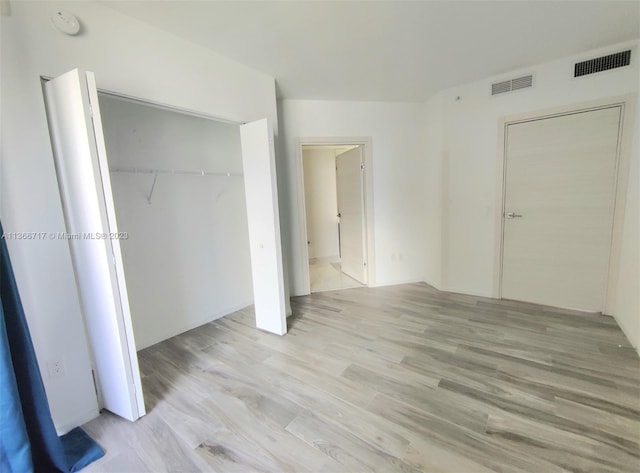 unfurnished bedroom featuring light hardwood / wood-style floors and a closet