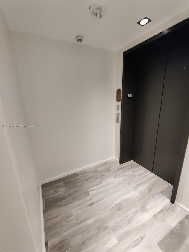 empty room with elevator and light hardwood / wood-style flooring