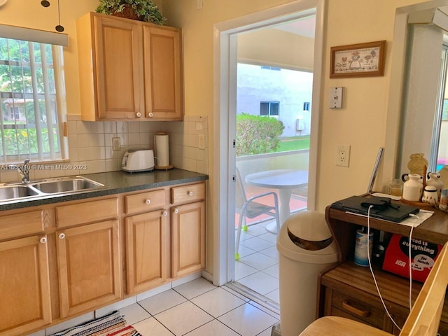 kitchen with tasteful backsplash, decorative light fixtures, light tile flooring, and sink