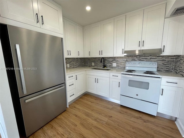 kitchen featuring electric stove, sink, stainless steel fridge, white cabinetry, and light wood-type flooring