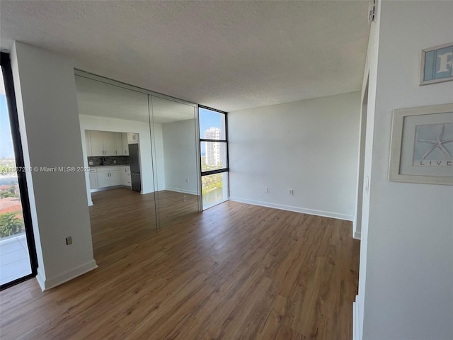 unfurnished room featuring hardwood / wood-style flooring, a wall of windows, and a textured ceiling