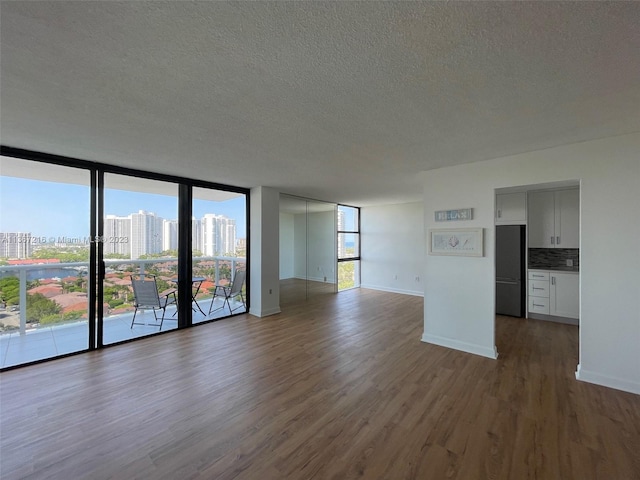 unfurnished living room featuring dark hardwood / wood-style flooring, expansive windows, and a textured ceiling