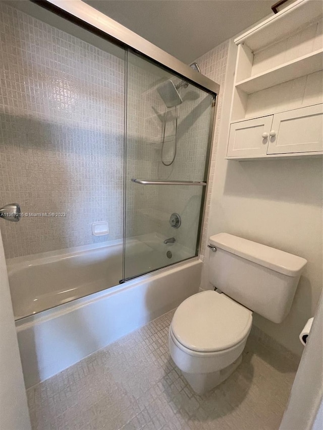 bathroom with toilet and shower / bath combination with glass door