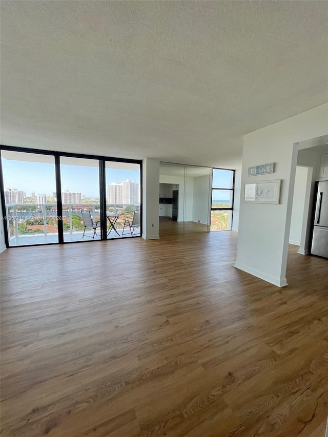 unfurnished living room featuring expansive windows, hardwood / wood-style floors, and a textured ceiling