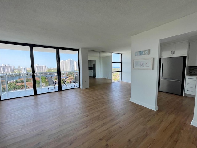 unfurnished living room featuring hardwood / wood-style flooring, a wall of windows, and a textured ceiling