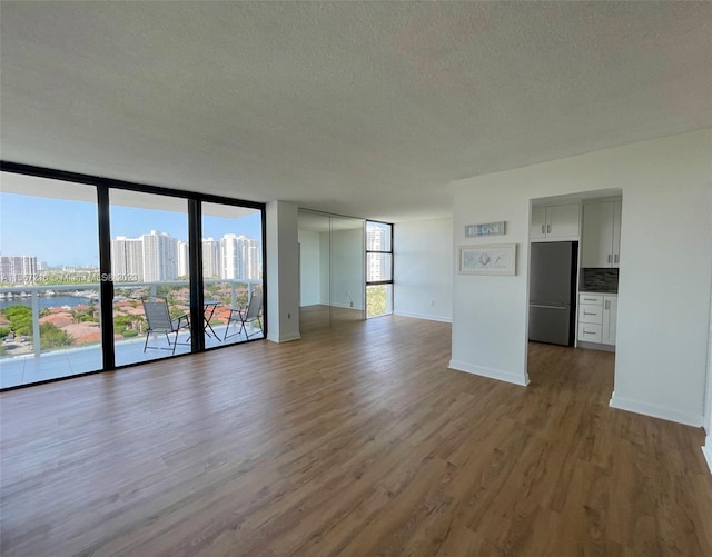 unfurnished living room with hardwood / wood-style flooring, a wall of windows, and a textured ceiling