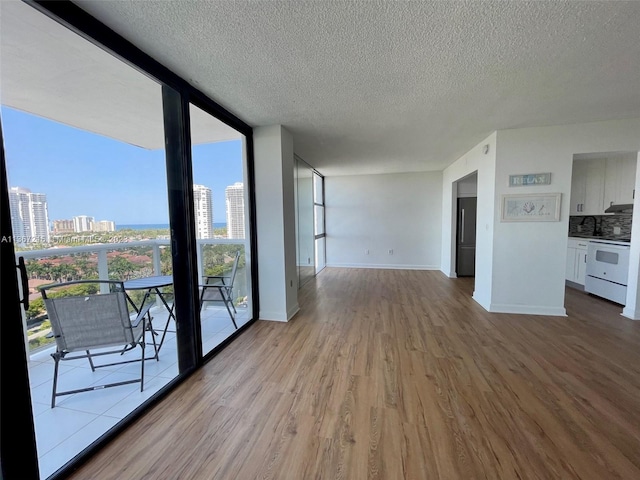 unfurnished living room with light wood-type flooring, a textured ceiling, and a wall of windows