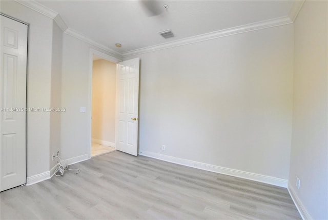 empty room featuring light wood-type flooring and crown molding