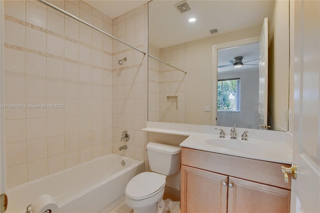 full bathroom featuring ceiling fan, tile floors, tiled shower / bath, vanity with extensive cabinet space, and toilet