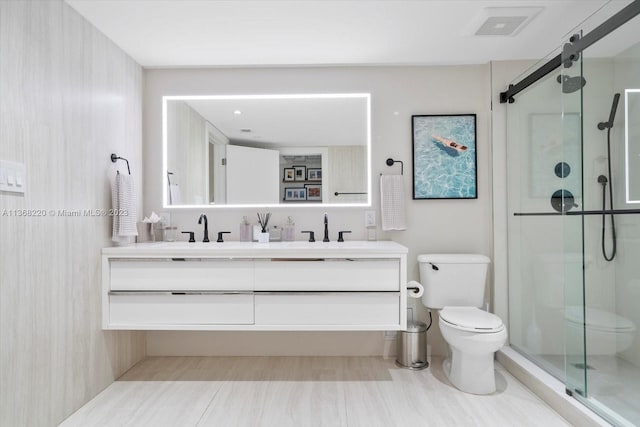 bathroom featuring dual vanity, tile flooring, a shower with shower door, and toilet