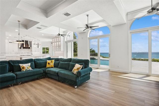 living room with a water view, coffered ceiling, and light wood-type flooring