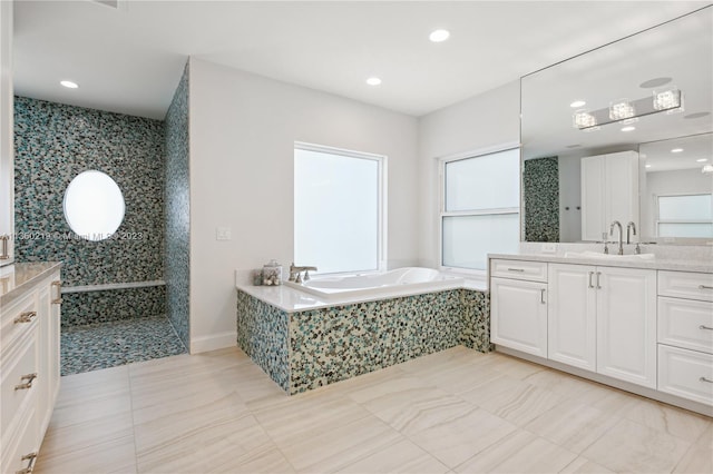 bathroom featuring a relaxing tiled bath, tile flooring, and vanity