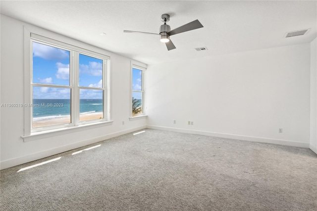 carpeted spare room with ceiling fan and a water view