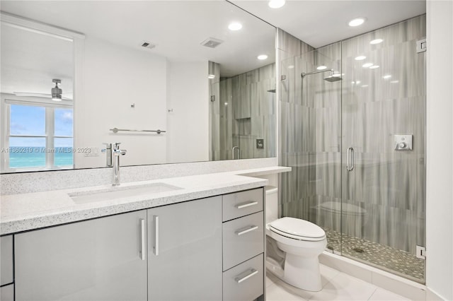 bathroom with vanity, ceiling fan, tile flooring, toilet, and a shower with shower door