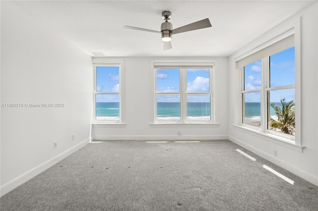 spare room with ceiling fan, a wealth of natural light, and a water view