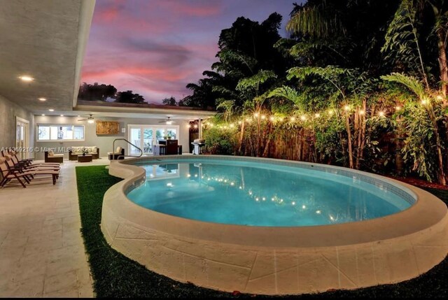 pool at dusk featuring a patio