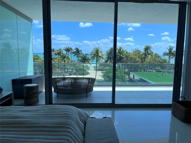 bedroom featuring a wall of windows and light tile floors