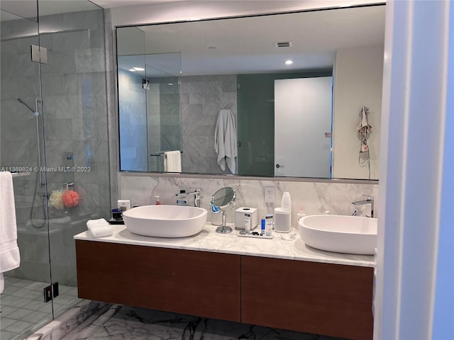 bathroom with tile walls, oversized vanity, an enclosed shower, and double sink