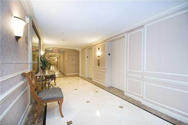 corridor with ornamental molding, light tile floors, and elevator