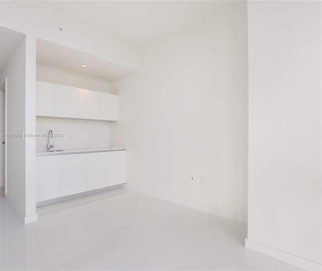 interior space with sink, white cabinets, and light tile flooring