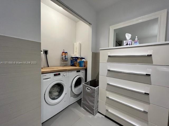 clothes washing area with washing machine and clothes dryer, electric dryer hookup, and light tile floors