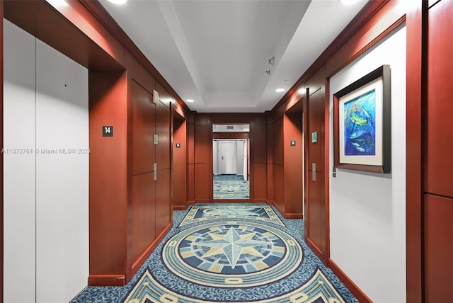 corridor with dark tile floors and a tray ceiling