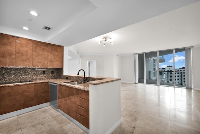 kitchen with light tile floors, kitchen peninsula, tasteful backsplash, light stone counters, and an inviting chandelier