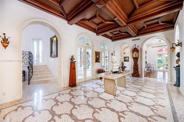 foyer with coffered ceiling, beamed ceiling, wooden ceiling, crown molding, and french doors