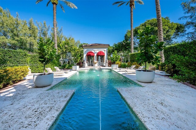 view of swimming pool with pool water feature and a patio