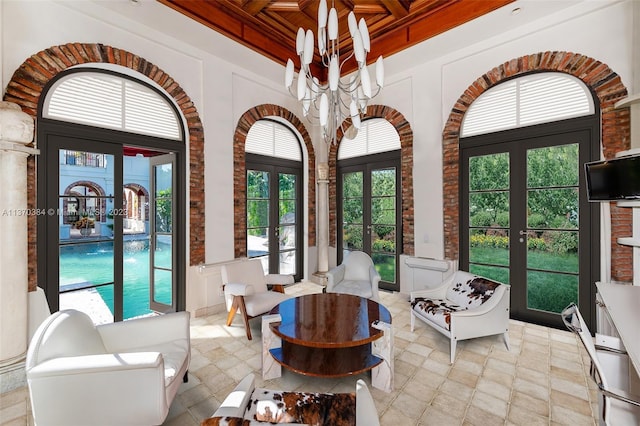 interior space with an inviting chandelier, plenty of natural light, french doors, and coffered ceiling