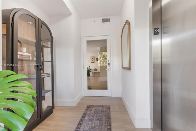 foyer entrance with elevator and light wood-type flooring