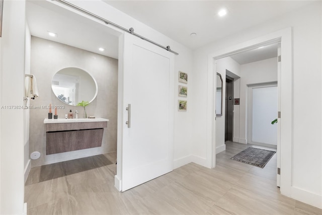 hallway featuring a barn door, sink, and light tile floors