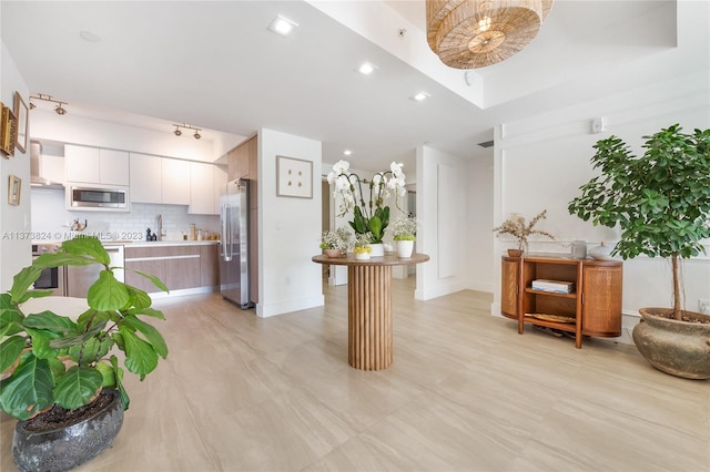 interior space featuring appliances with stainless steel finishes, sink, white cabinets, tasteful backsplash, and wall chimney exhaust hood