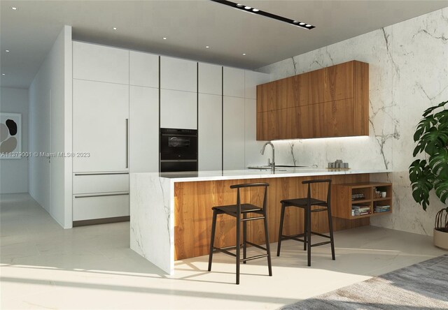 kitchen featuring white cabinetry, kitchen peninsula, sink, and backsplash