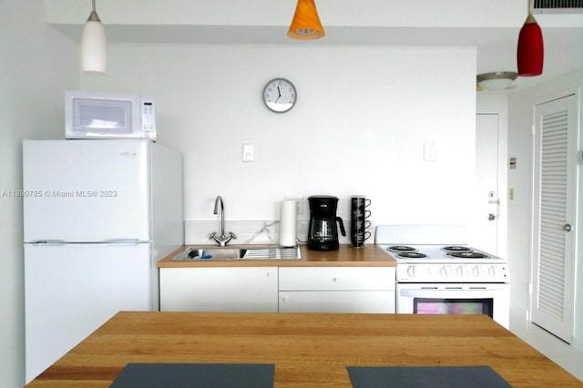 kitchen with white appliances, white cabinetry, hanging light fixtures, and sink