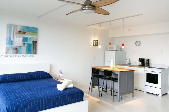 bedroom featuring ceiling fan, white fridge, light wood-type flooring, and sink